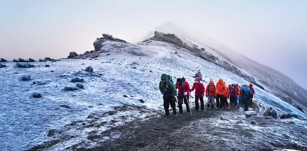 Climber reaching the summit of Mount Kilimanjaro with glaciers in the background